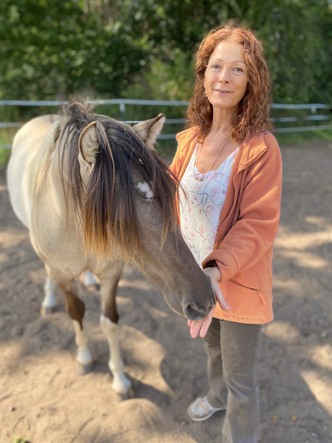 Corinna wilhelms Tierheilung neben einem Pferd
